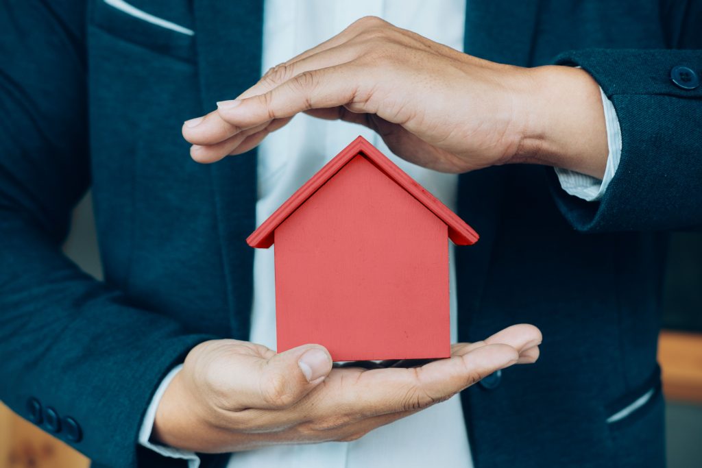 man in suit holding red toy house